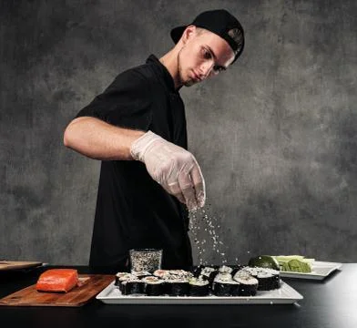 Cook's hands close-up. A male chef makes sushi and rolls from rice, red fish and Stock Photos