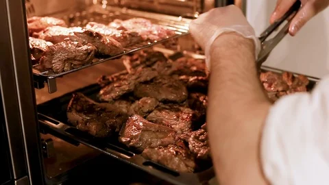 Cook's hands preparing meat steaks on baking tray in oven Stock Footage 111072150