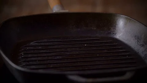 The cook's hands putting two pieces of smoked bacon on the hot broiler pan. 4K Video stock 82357152