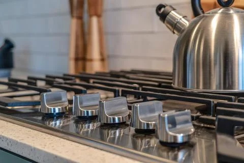 Cooktop with five knobs and kettle on top of the burner with cast iron grate Stock Photos