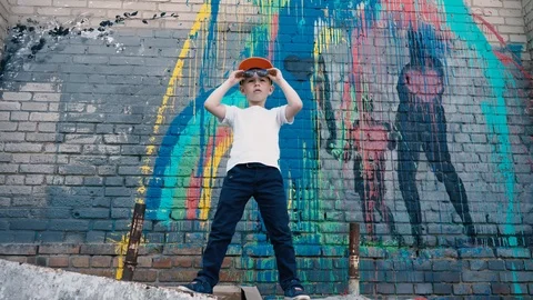 A cool 5 year old child dances in sunglasses near a brick wall with graffiti, a Stock Footage 89688580