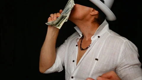 Cool bad guy with a black mask, white hat, cigar and money on a black backdrop Stock-Footage 142542804