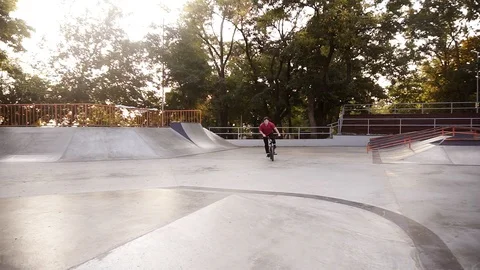 Cool bmx biker in red T-shirt and black sporty pants jumping, doing 360 degrees Stock Footage 118963802