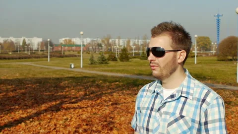 Cool caucasian guy in black glasses and shirt smokes vape, outside, slow motion Video stock 102306939