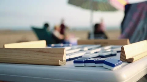 Cool close-up of Dominoes on a table at beach with people in the background Stock Footage 63889477