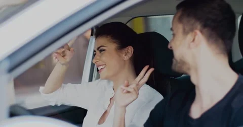 Cool couple having fun singing and dancing while driving car. Charming brunette Stockbeeldmateriaal 65417080