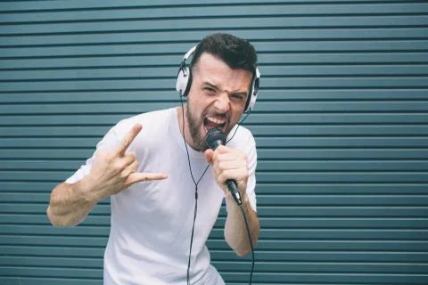 Cool dude is standing and posing on camera. He is screaming in mic and showin Stock Photos