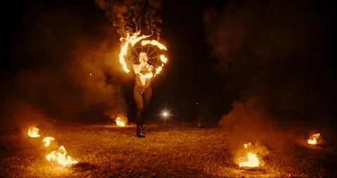 Cool female fire show stuntsman performing, swinging her burning fans, standing Video stock 101005667