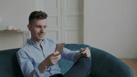 Cool guy buy online with cell phone and bank card at home. Elegant ambitious man Stock Footage 107788489