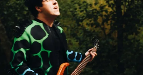 Cool guy in a raincoat jumps and plays bass guitar. Very fun and emotional Stock Footage 114520155