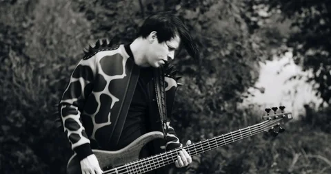 Cool guy in a raincoat playing bass guitar and spinning around Stock Footage 114520221