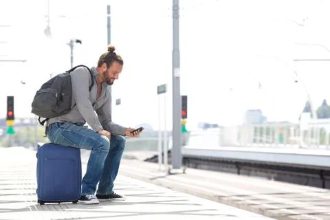 Cool guy sitting on suitcase waiting for train Foto stock