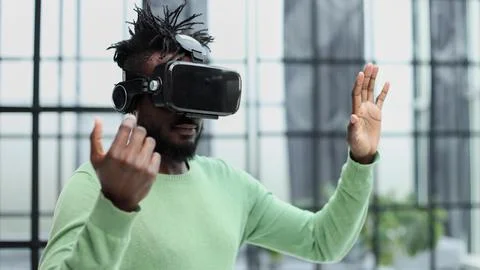 Cool handsome african american man put on virtual reality goggles for the first Stock Photos