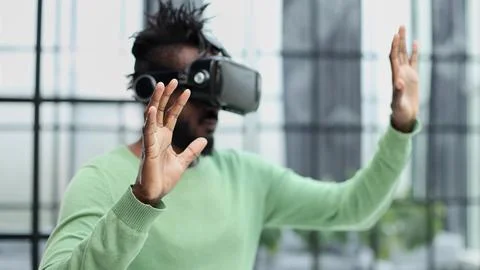 Cool handsome african american man put on virtual reality goggles for the first Stock Photos