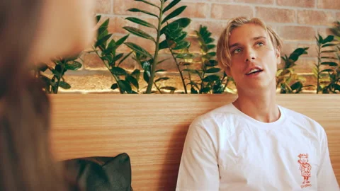 Cool handsome guy having a conversation with his girl friend in interior cafe wi Stock Footage 199455927