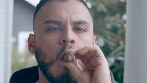 Cool hispanic man smoking cigar blows smoke out of mouth Stock Footage 84491338