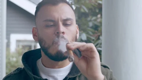 Cool hispanic man smoking cigar blows smoke out of mouth Stock Footage 84491983