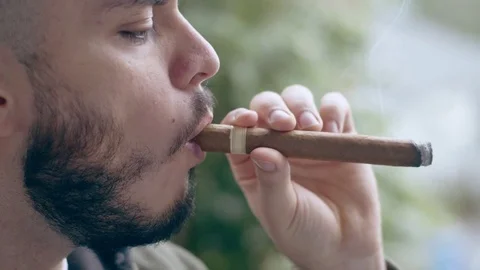 Cool hispanic man smoking cigar blows smoke out of mouth Stock Footage 84493648