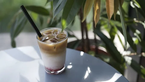 Cool iced coffee with milk and syrup in a summer cafe under the shadow of leaves Stock Footage 129257633
