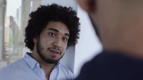 Cool looking middle eastern man with afro chatting in office Stock Footage 67345477