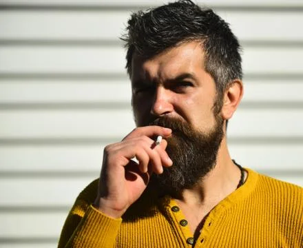 Cool macho man with beard and warm clothes smoking Stock Photos