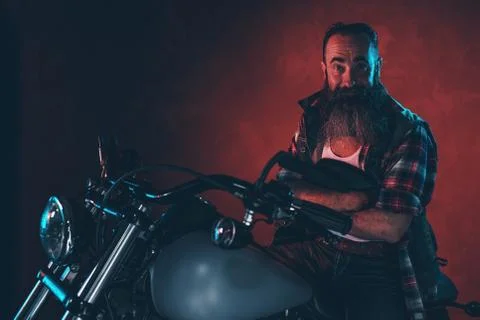 Cool man with long gray beard on motorcycle at night. Stock Photos