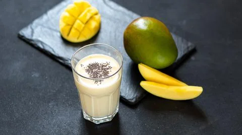 Cool mango milkshake on a black background. A drink to quench your thirst in the Stock Photos