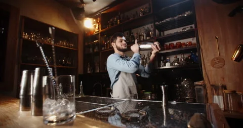 Cool professional caucasian bartender making a cocktail, shaking his shaker Stock Footage