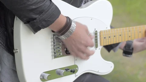 Cool rock guy plays a white electric fender guitar outside Stock Footage 107084356