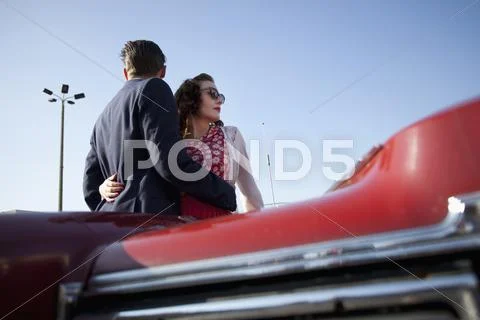 A cool, rockabilly couple with arms around each other by a vintage car Stock Photos