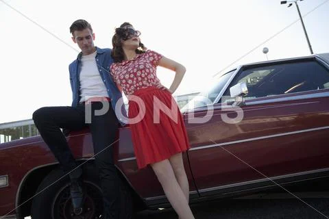 A Cool, Rockabilly Couple Leaning Against A Vintage Car