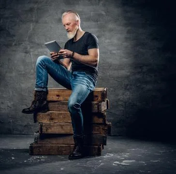 Cool senior man with tablet posing around firewoods 库存照片