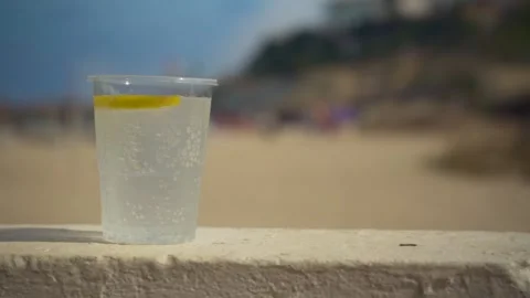 Cool soft drink with bubbles, lemon circle on top at a stone fence in holid.. Stock Footage 345430876