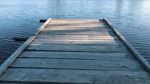 Cool view on tranquil blue water in the lake from an old wooden pier/bridge in Video stock 116465603