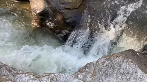 The cool waterfall is falling strongly among the huge brown rocks Stock Footage 155039460