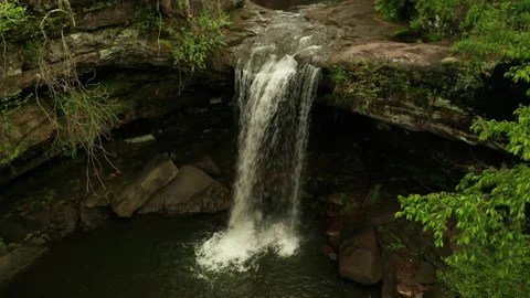 Cool waterfall flowing over cliff in front of a cave Stock Footage 153874267