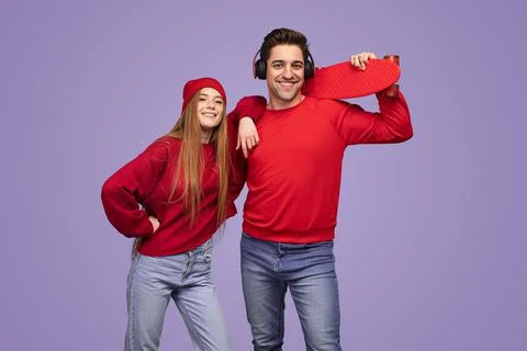 Cool young couple with skateboard smiling at camera in violet studio Stock Photos