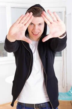 Cool young guy in hooded jacket framing his face with hands Stock Photos