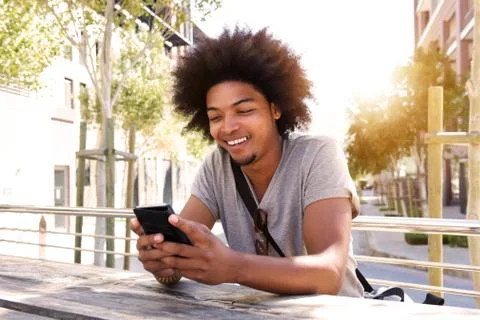 Cool young guy sitting outside with mobile phone Stock Photos