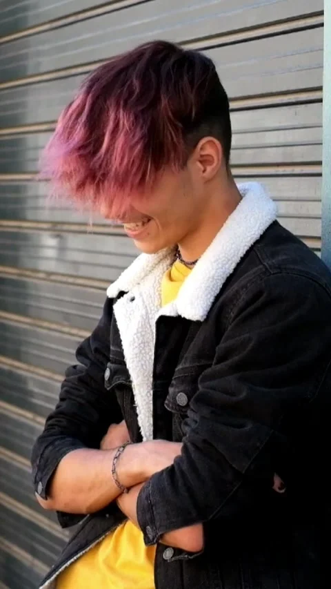 Cool young man with pink dyed hair and a lip piercing posing with arms crossed Stock Footage 346607937
