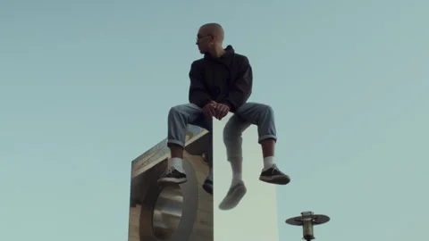 Cool young man sitting on a reflective box outdoors 스톡 동영상 258200837