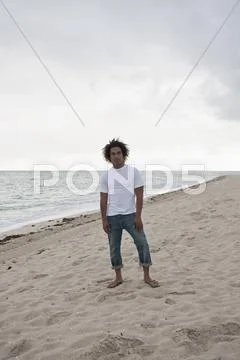 A cool young man standing on a beach, front view Stock Photos