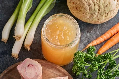 Cooled congealed beef bone broth in a glass jar, with vegetables and marrow b Stock Photos