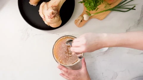 Cooled dense gelatinous bone broth tested for texture with spoon on marble Stock Footage 344032149
