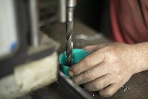 Cooling drill on a drilling machine. Work with a drill in a metal workshop. Stock Photos