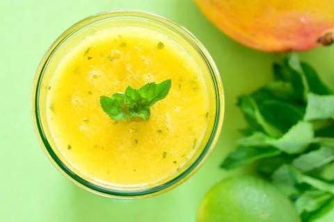 Cooling Mango mint smoothie, summer drink on green table, Yellow Tropical Smo Stock Photos