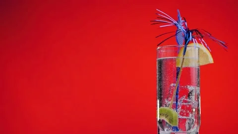 Cooling summer drink with lemon and kiwi rotate on a red background. Stock Footage 131229375
