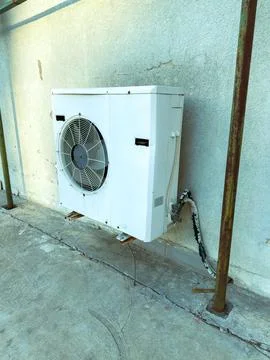 Cooling unit mounted on a wall near a concrete surface in a residential are.. Stock Photos