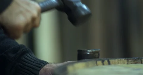 Cooper craftsman hammers iron hoops onto whiskey barrel keg 動画素材 100736228