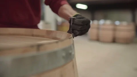Cooper using hammer to tighten metal hoop on barrel, close up tracking shot Stock Footage 121583313